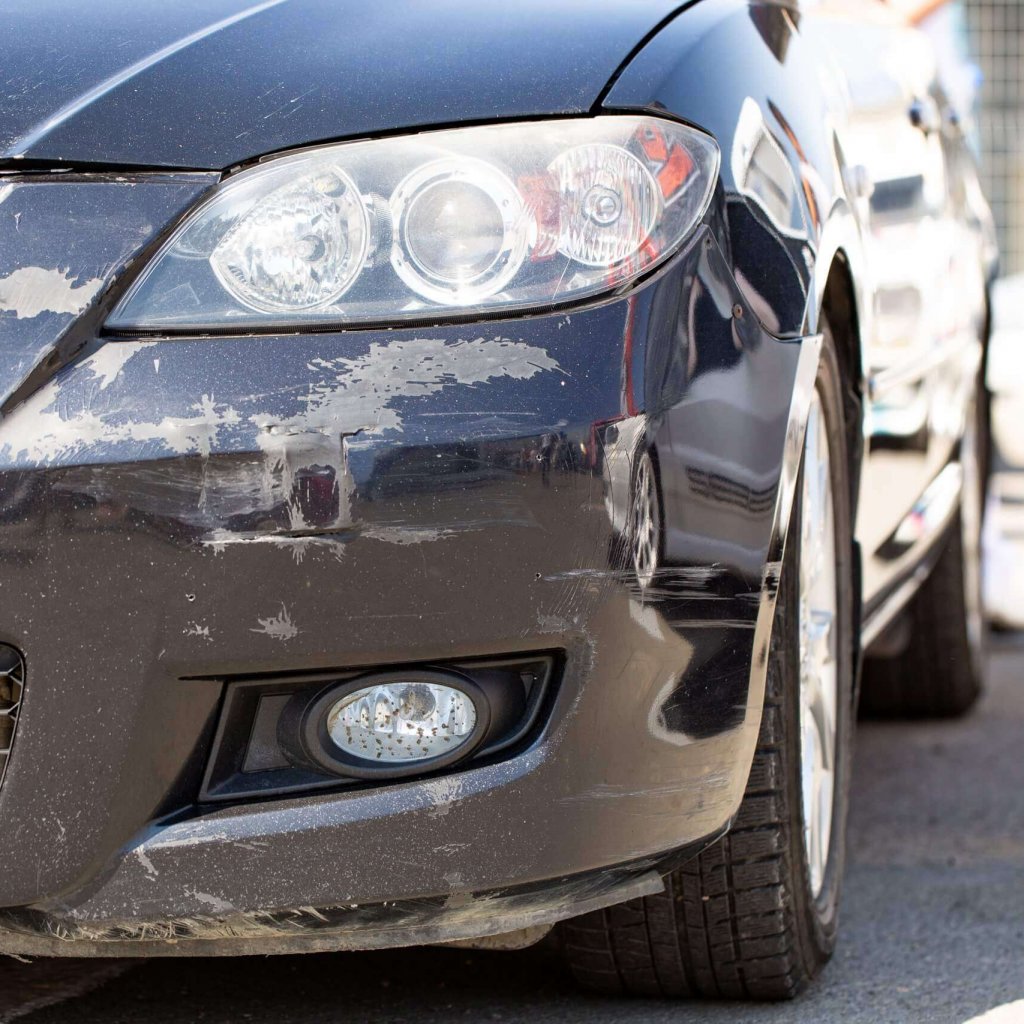 nahaufnahme-eines-schwarzen-autos-mit-einer-zerrissenen-stossstange-und-schaden-am-scheinwerfer-des-fahrzeugs-scaled